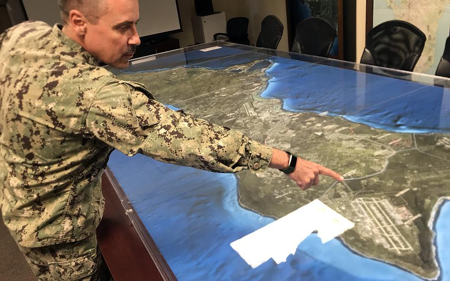 Navy Cmdr. Brian Foster, who is helping oversee construction for the Naval Facilities Engineering Command on Guam, points out some of the planned facilities on a tabletop map, Feb. 20, 2020.