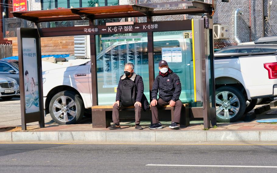 People wait for a public bus outside Camp Humphreys, South Korea, March 16, 2020.