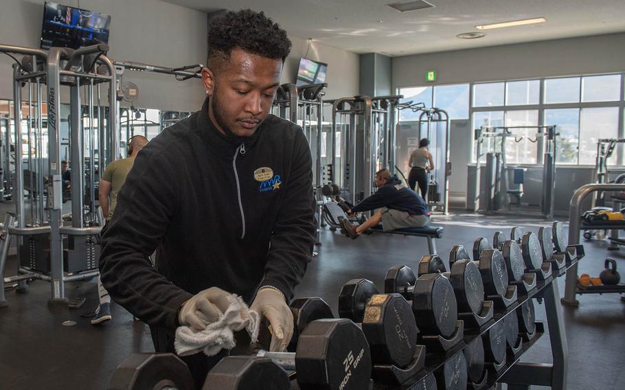 Malik Cooper, a recreation assistant for the fitness center at Sasebo Naval Base, Japan, cleans equipment on Wednesday, March 25, 2020. 