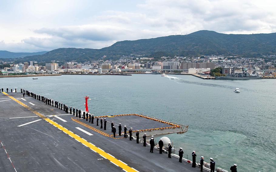 Sailors man the rails as the amphibious assault ship USS America arrives in Sasebo, Japan, Dec. 6, 2019. 