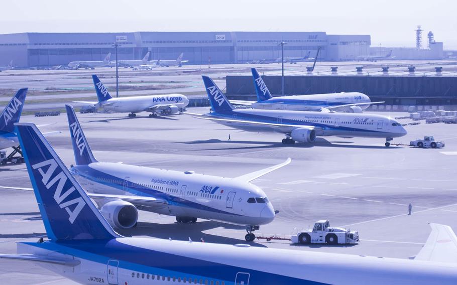 Commercial jets are pulled to their gates at Haneda International Airport in Tokyo, March 18, 2020. 