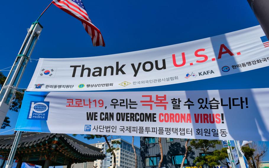 An American flag waves alongside coronavirus banners outside Camp Humphreys, South Korea, March 16, 2020.

