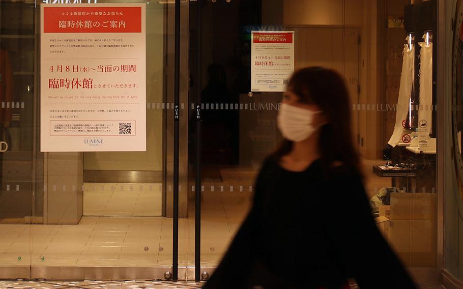 A woman strolls past a Tokyo department store that's closed because of the coronavirus, April 9, 2020. 