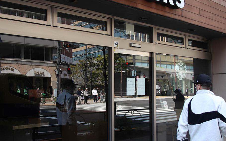 A man glances at a Starbucks in central Tokyo that's been shuttered because of the coronavirus, April 9, 2020. 