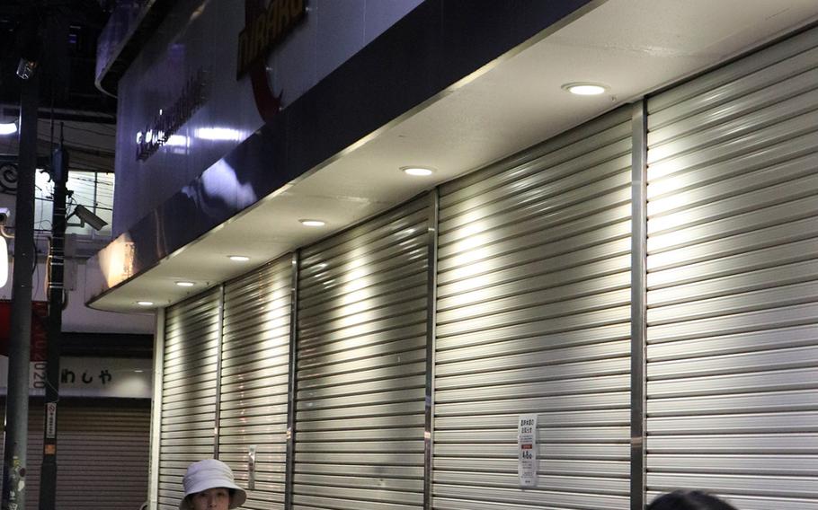 Pedestrians stroll past a shuttered pachinko parlor in the Nakano section of Tokyo, Sunday, May 3, 2020. 