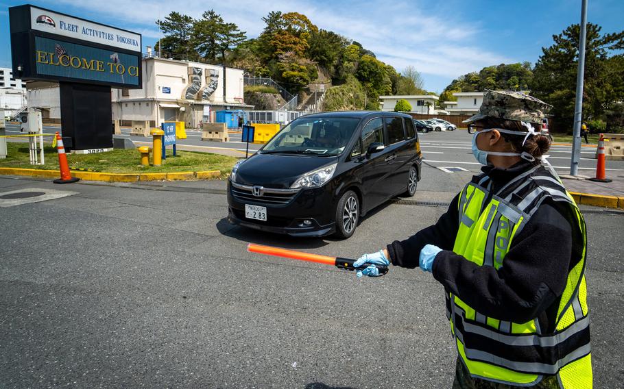 A sailor directs a vehicle toward a coronavirus screening station at Yokosuka Naval Base, Japan, April 10, 2020. 
