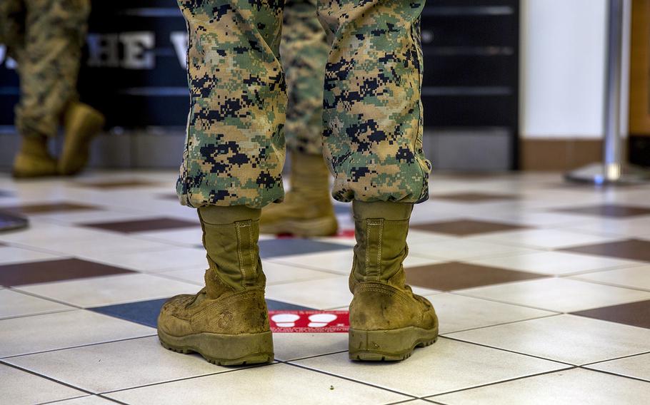 A Marine stands behind a social distancing floor marker while waiting in line at the exchange at Camp Hansen, Okinawa, April 7, 2020.