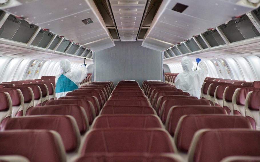 A sanitation crew works to disinfect the chartered Boeing 767 known as the Patriot Express at Osan Air Base, South Korea, Tuesday, July 14, 2020.