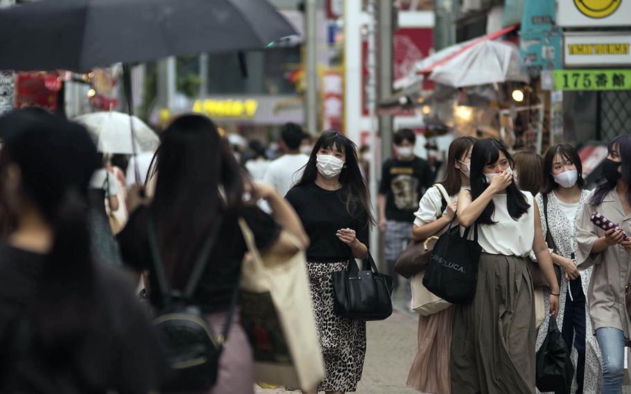 People wear masks as they stroll Takeshita Street, a pedestrian area lined with fashion boutiques, cafes and eateries in Harajuku, Tokyo, Monday, July 27, 2020.
