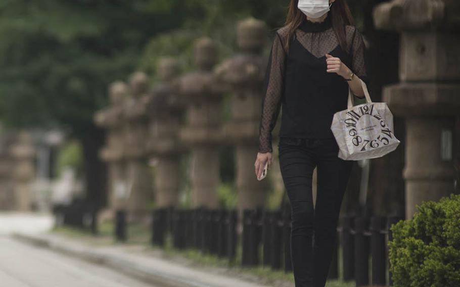 A mask-wearing woman walks near Yasukuni Shrine in central Tokyo, Monday, July 27, 2020. 