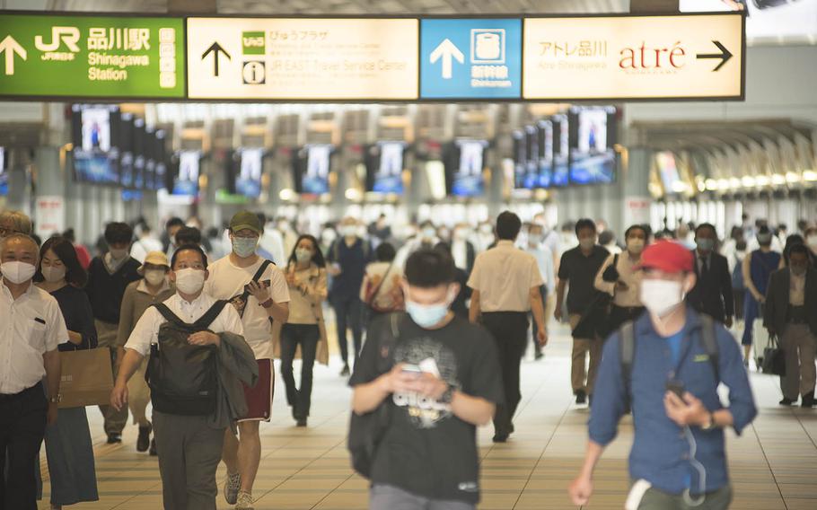 Commuters wearing masks make their way through Shinagawa Station on a recent afternoon in central Tokyo. 
