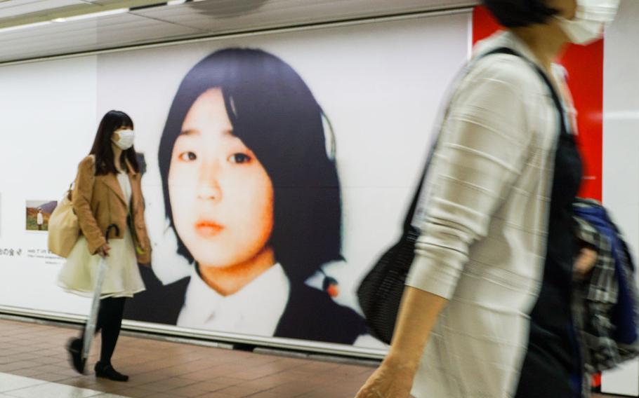 Commuters walk past photos of Megumi Yokota, who was abducted by North Koreans in 1977, at Shinjuku Station in Tokyo, May 9, 2018. 