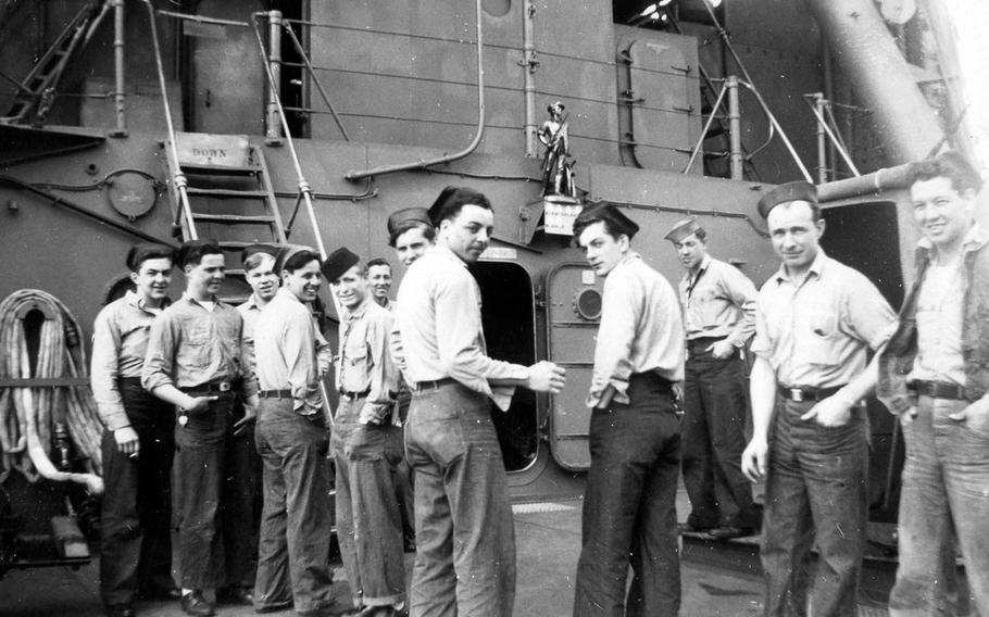 Crewmen of the USS Concord stand on the main deck below a statue of a minuteman mounted on the bulkhead, in this photo taken during the last 15 months of World War II. 