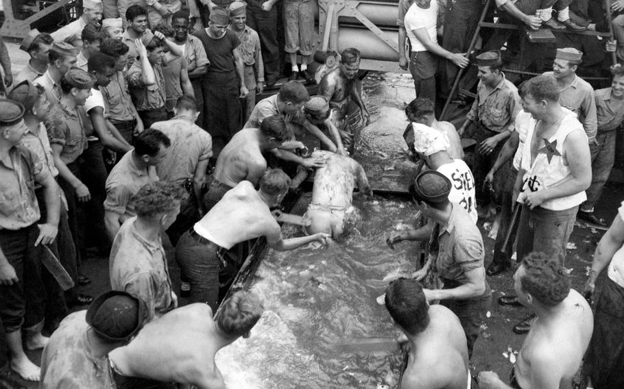 A sailor aboard the USS Concord undergoes a shellback initiation as the ship crosses over the equator in the Pacific Ocean during World War II. 