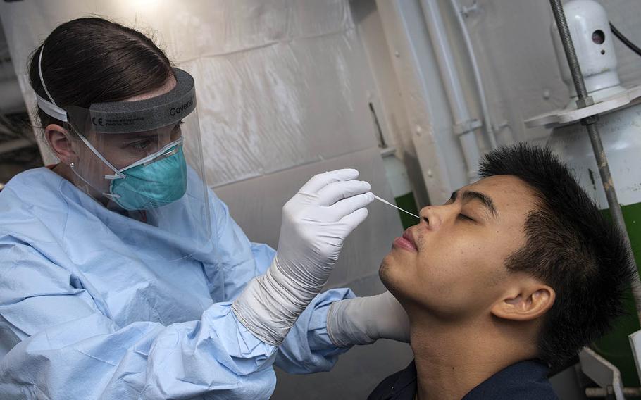 Petty Officer 1st Class Ellysan Roe, a hospital corpsman, collects a nasal swab sample from Petty Officer 2nd Class Alec Cervana during coraonvirus testing aboard the USS New Orleans while at sea near Japan, Aug. 12, 2020. 