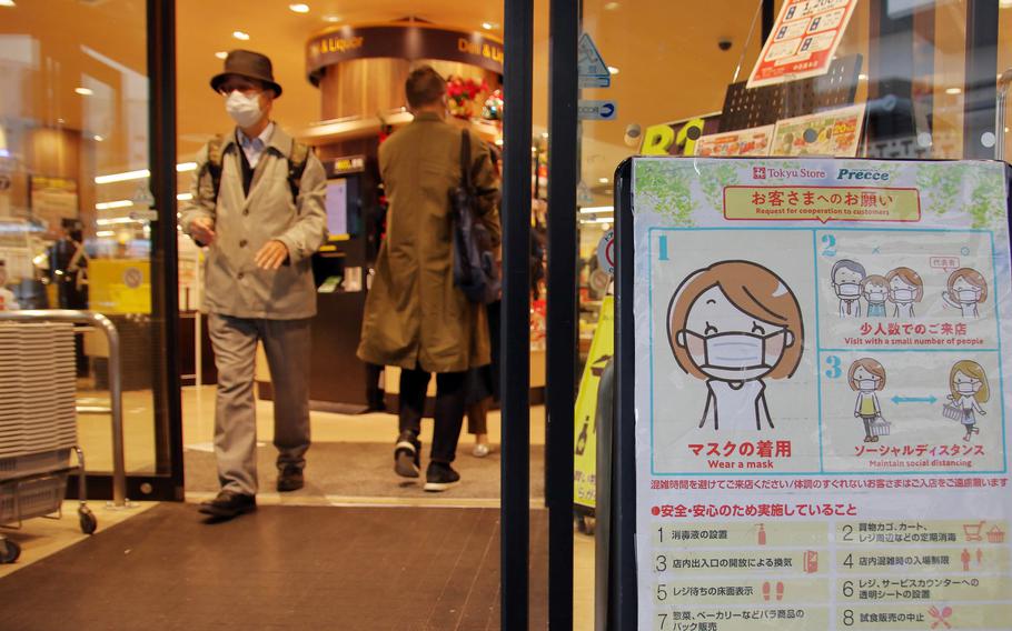 A sign outside a grocery store in central Tokyo reminds shoppers to practice anti-coronavirus measures, Tuesday, Nov. 17, 2020. 