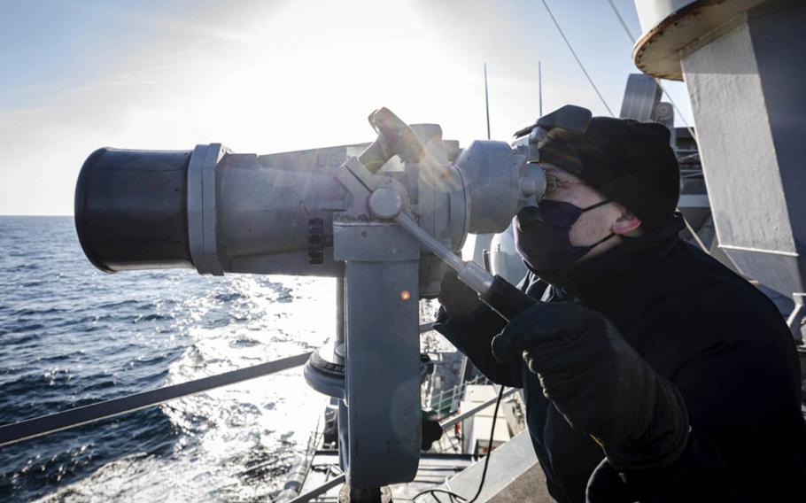 Ensign James Bateman, of Huntsville, Ala., scans the horizon aboard the USS John S. McCain as the guided-missile destroyer sails through Peter the Great Bay in the Sea of Japan, Tuesday, Nov. 24, 2020.
