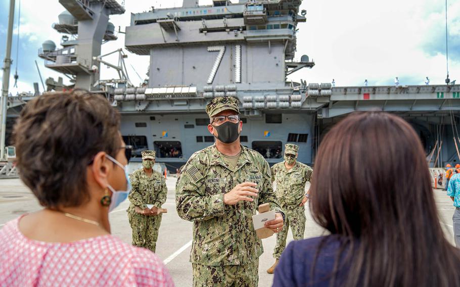 Guam Gov. Lou Leon Guerrero, left, listens as Rear Adm. John Menoni, commander of Joint Region Marianas, speaks outside the USS Theodore Roosevelt ahead of the virus-stricken carrier's departure from Naval Base Guam, June 4, 2020.