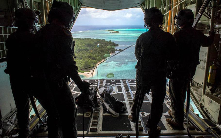 Loadmasters with the 36th Airlift Squadron out of Yokota Air Base, Japan, watch bundles parachute down to Nomwin, Federated States of Micronesia, Dec. 13, 2019, during the annual Operation Christmas Drop.