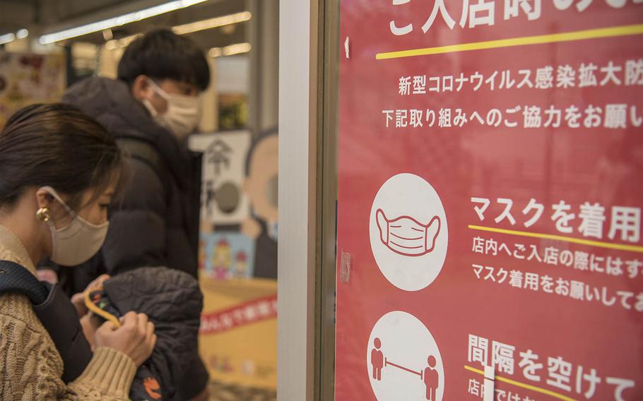 A sign reminds patrons to wear masks and practice social distancing at a shop near Kamiooka Station in Yokohama, Japan, Wednesday, Dec. 2, 2020. 