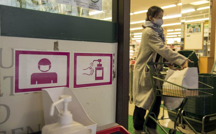 Signs warn customers to wear masks and sanitize their hands before entering a shop in Yokohama, Japan, Dec. 2, 2020. 