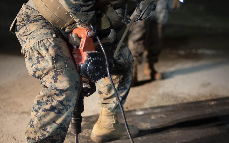 A combat engineer from Marine Wing Support Squadron 171 uses a hammer drill to secure a fiberglass panel to a concrete pad to cover up damage from a simulated missile strike during an exercise at Marine Corps Air Station Iwakuni, Japan, Oct. 29, 2020. 