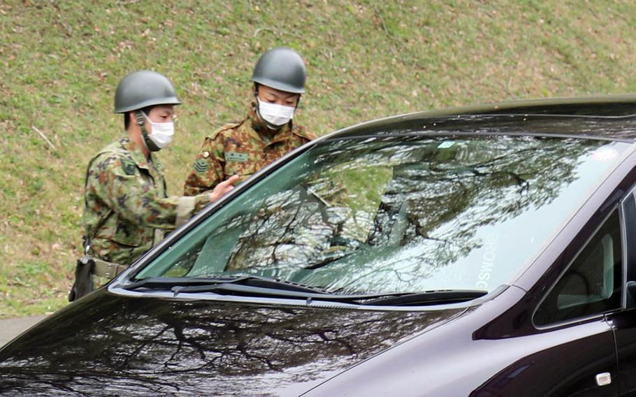 Members of the Japan Ground Self-Defense Force check a driver for coronavirus symptoms at Camp Zama, Japan, March 31, 2020.