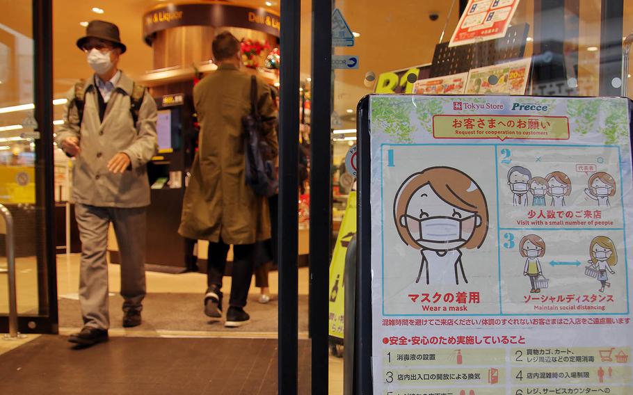 A sign reminds patrons to wear masks and practice social distancing at a shop in central Tokyo, Nov. 17, 2020.
