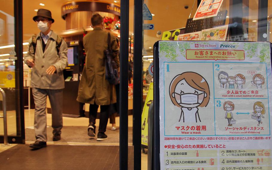 A sign reminds patrons to wear masks and practice social distancing at a shop in central Tokyo, Nov. 17, 2020. 