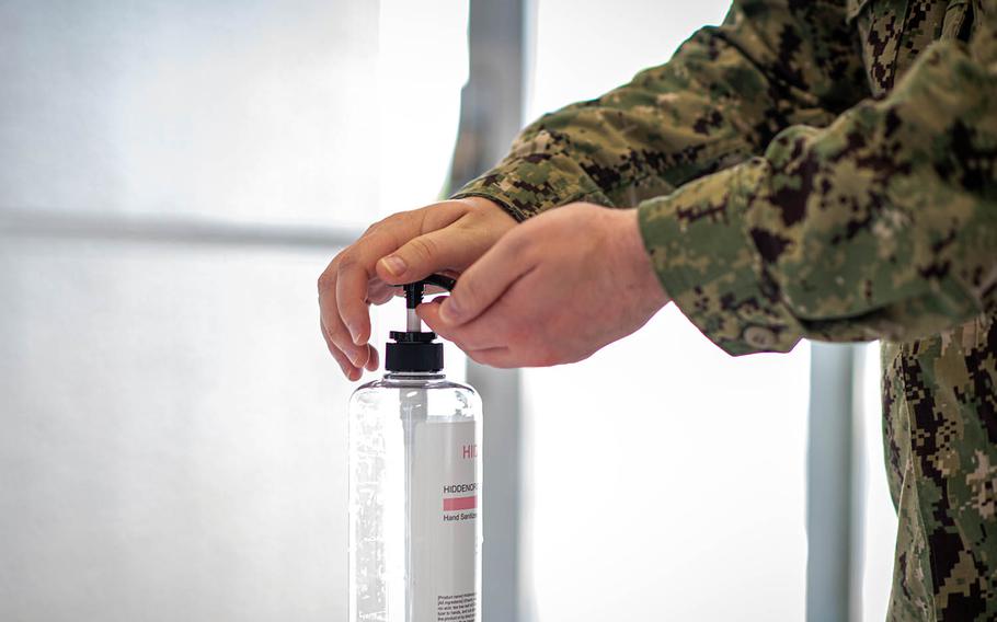 A sailor sanitizes his hands before entering the Navy Exchange at Yokosuka Naval Base, Japan, Aug. 13, 2020. 