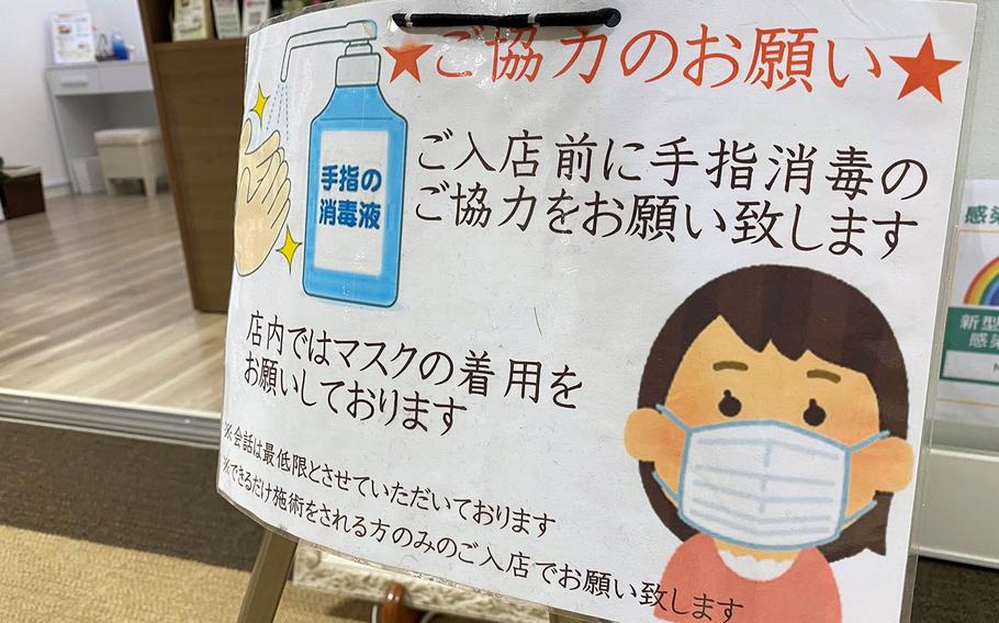 A sign outside a shop in western Tokyo reminds patrons to wear a mask and sanitize their hands, Thursday, Dec. 17, 2020.