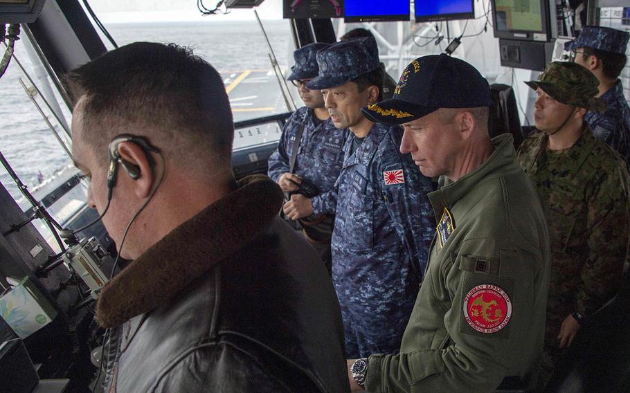 Capt. Luke Frost, commander of the USS America, and Japanese Rear Adm. Shirane Tsutomu watch flight operations aboard the amphibious assault ship in the East China Sea, Jan. 13, 2020.