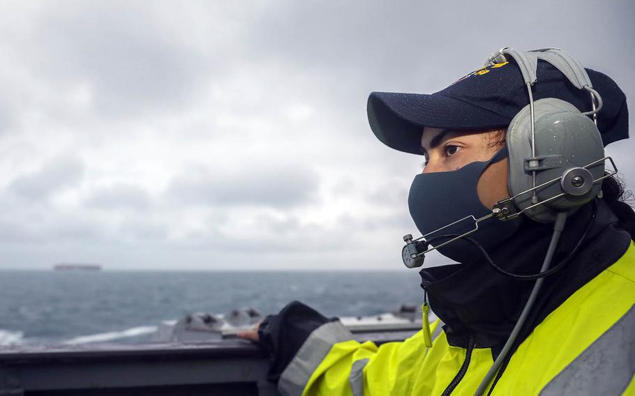 Petty Officer 1st Class Isis Hernandez, of Albuquerque, N.M., stands lookout watch on the bridge wing as the guided-missile destroyer USS Mustin sails in the East China Sea, Friday, Dec. 18, 2020. 