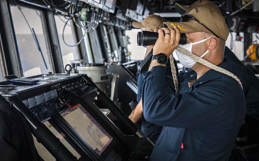 Cmdr. Ryan T. Easterday, commander of the USS John S. McCain, scans the horizon in the South China Sea from the pilot house on Dec. 22, 2020.