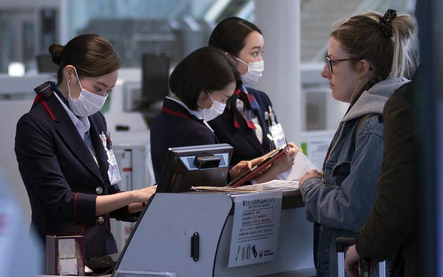 Airline ticket agents at Haneda Airport process passengers for boarding on March 18, 2020. Japan is imposing a temporary ban on incoming nonresident foreigners starting Dec. 28, 2020.