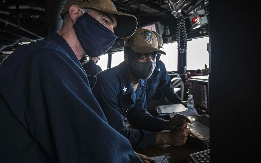 Navigator Lt. j.g. Daniel Feeney, left, from Old Greenwich, Conn., and Quartermaster 2nd Class Asah Favors, from Suffolk, Va., review the USS John S. McCain's course in the South China Sea on Dec. 22, 2020.