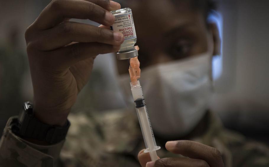 Air Force Staff Sgt. Shakeyla Moses, 25, from Columbus, Ga., prepares a dose of the Moderna coronavirus vaccine at Yokota Air Base, Japan, on Monday, Dec. 28, 2020. 