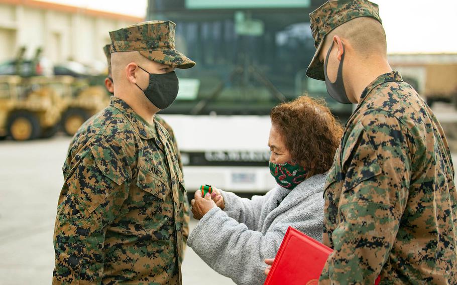 Sgt. John James is awarded the Navy Achievement Medal by Tokiko Ahuso, whom James assisted after she was bitten by a snake on Okinawa. The ceremony took place at Camp Hansen, Okinawa, Japan, on Dec. 23, 2020. 