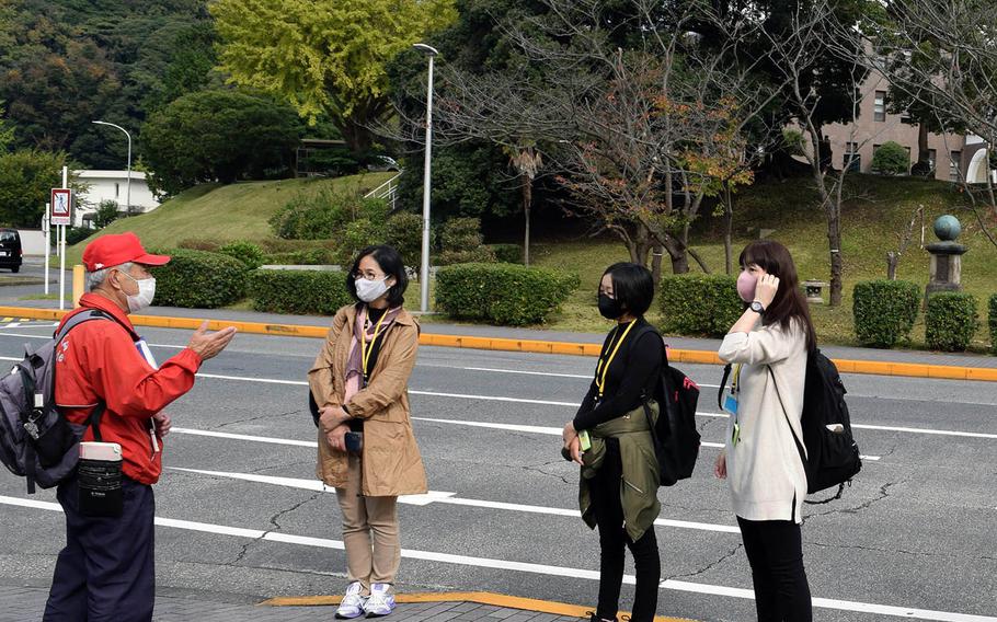 A volunteer guide provides a tour to visitors masked and socially distanced against the coronavirus at Yokosuka Naval Base, Japan, on Nov. 8, 2020.
