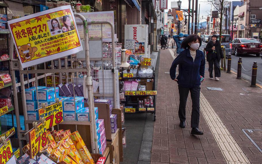 Pedestrians wearing masks as safeguards against the coronavirus walk along a street in Fussa, western Tokyo, Japan, on Jan. 5, 2021. 