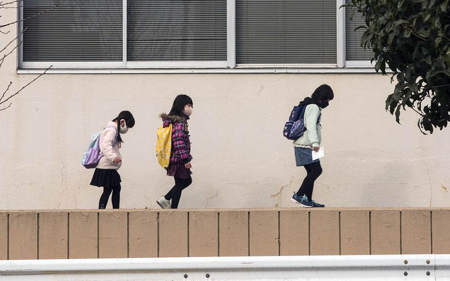 Children masked against the coronavirus make their way along a street in Fussa, Japan, on Jan. 5, 2020.