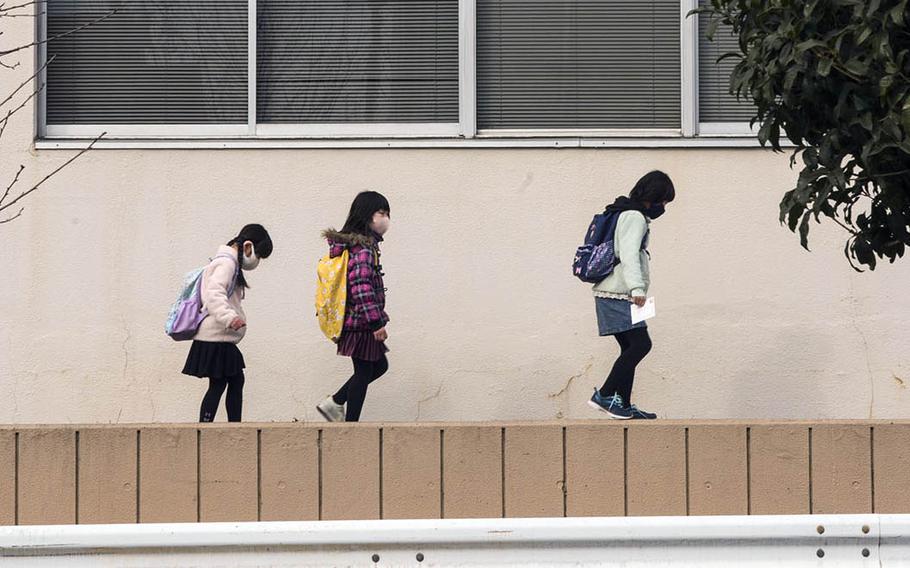 Children masked against the coronavirus make their way along a street in Fussa, Japan, on Jan. 5, 2020. 