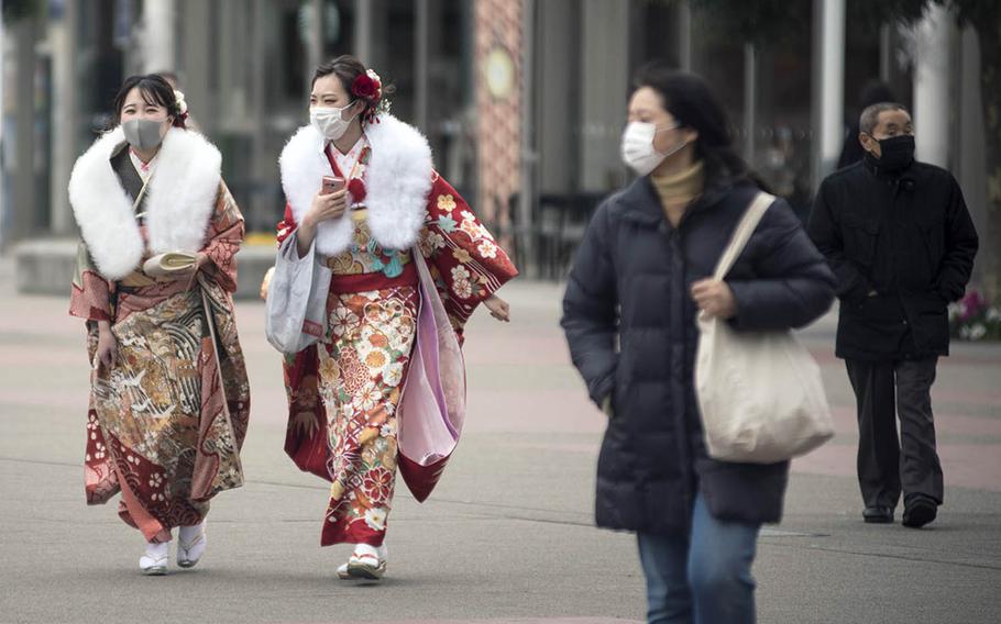Young women in Yokohama, Japan, dressed for the Japanese coming-of-age ceremony, wear masks as protection against the coronavirus, Monday, Jan. 11, 2021.