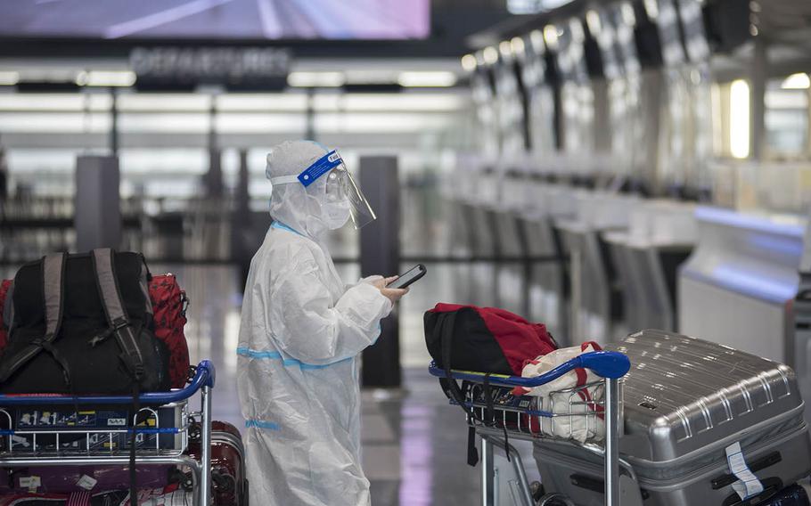 A passenger waits in a line at Narita International Airport outside Tokyo, Friday, Jan. 15, 2021. Across Japan, 19,080 people tested positive for the coronavirus between Friday and Monday, Jan. 18, 2021, according to the World Health Organization. 