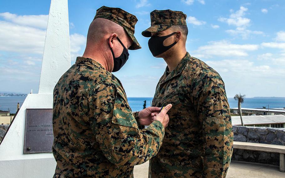 Sgt. Brandon Antoine, a 3rd Marine Division radio operator, receives the Navy and Marine Corps Medal from division commander Maj. Gen. James Bierman at Camp Courtney, Okinawa, Jan. 13, 2021.