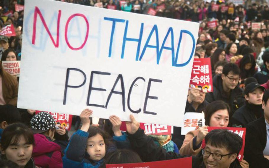 A child helps hold up a sign protesting the U.S. military's Terminal High Altitude Area Defense, or THAAD, missile-defense battery, during a gathering at Gwanghwamun Square in Seoul, South Korea, March 11, 2017.