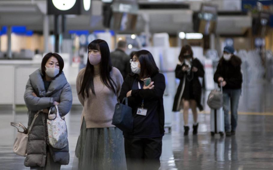 Travelers wear masks inside a terminal at Narita International Airport outside Tokyo, Jan. 15, 2021. 