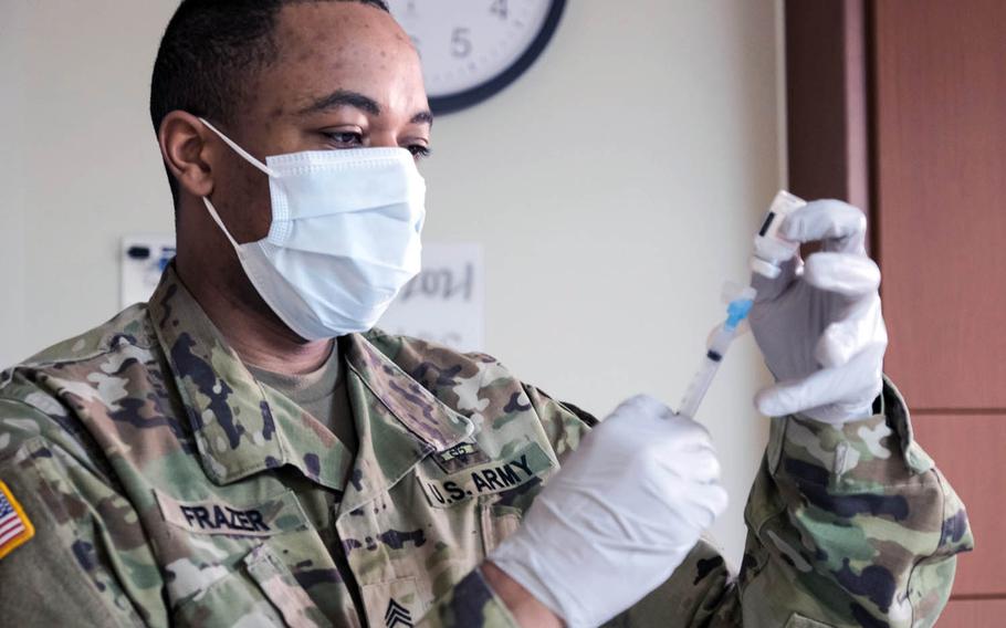 Army Staff Sgt. Shane Fraze prepares a dose of the Moderna coronavirus vaccine at Camp Humphreys, South Korea, Wednesday, Jan. 27, 2021.