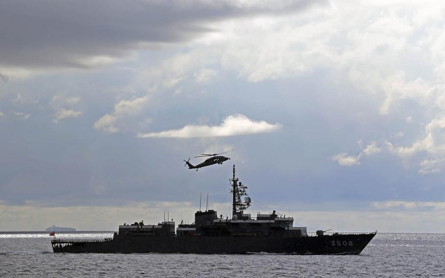 A Navy MH-60S Seahawk helicopter flies alongside the Japan Maritime Self-Defense Force ship JS Kashima in the South China Sea, June 23, 2020. 