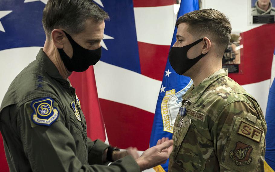 Staff Sgt. Seth Shannon receives the Air Force Achievement Medal from Lt. Gen. Kevin Schneider, commander of U.S. Forces Japan, at Yokota Air Base, Japan, Thursday, Jan. 28, 2021. Shannon was honored for his efforts to bring military working dogs to Japan during the pandemic. 